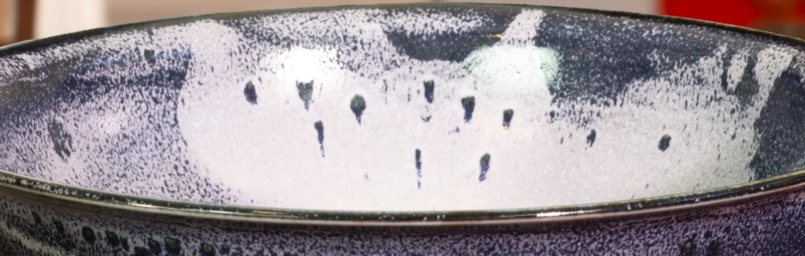 The bowl's interior filling the frame: white glaze breaking over deep aubergine, finely speckled where the two meet.