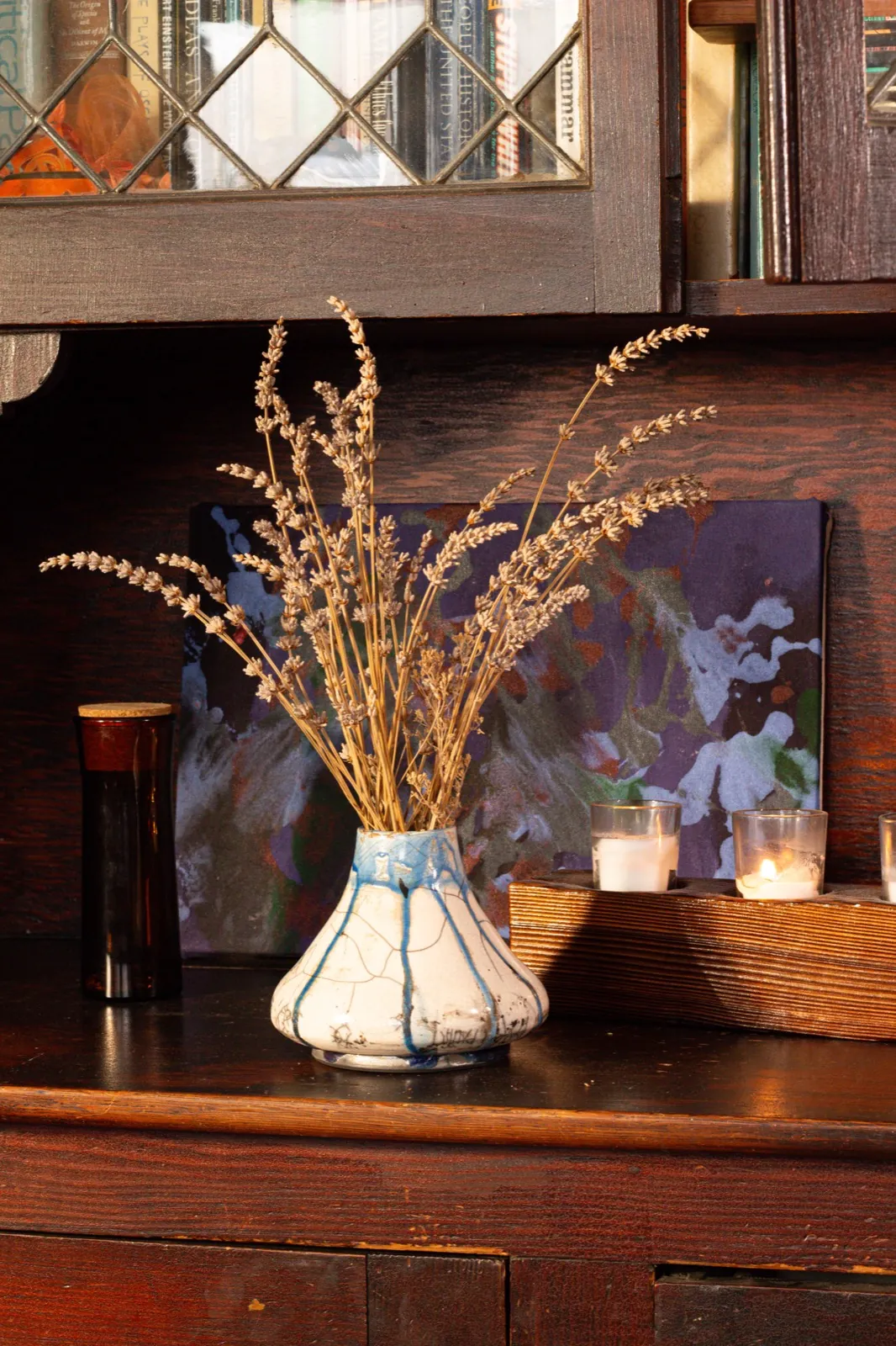 The crackle vase on a dark oak dresser in low evening light, dried lavender fanning out above it.
