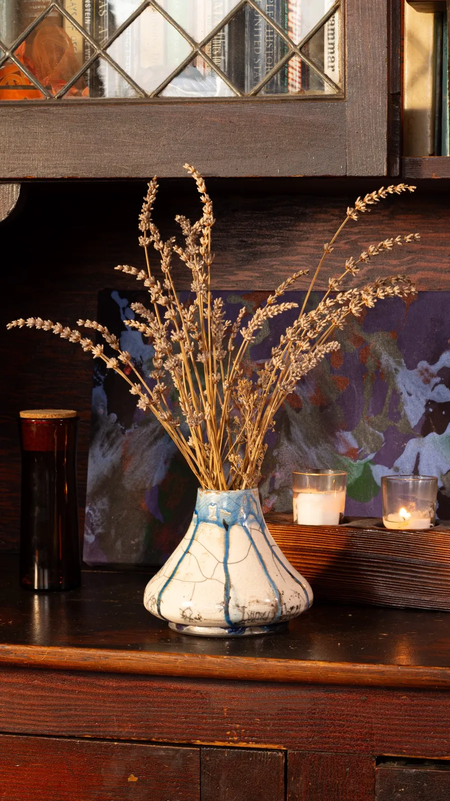 The same vase seen from slightly further back, a painting and two candles behind it.