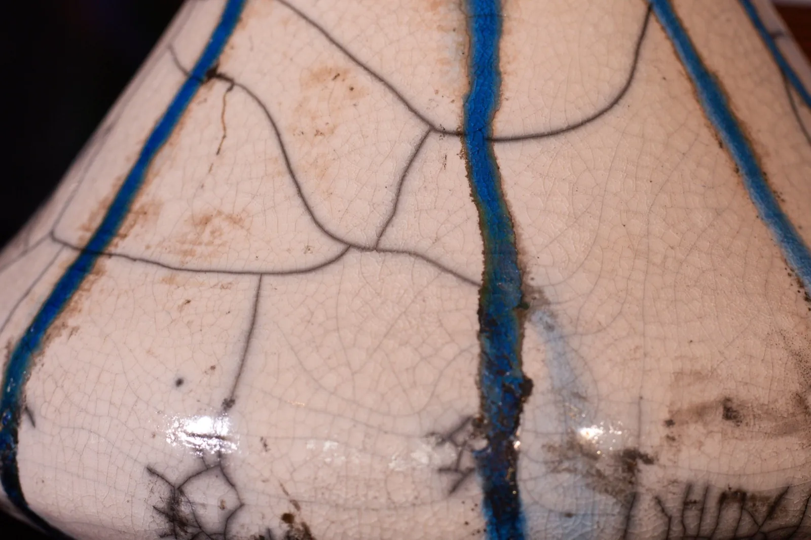 Macro detail of the crackle glaze: a fine web of brown and black crazing crossed by two vertical cobalt runs.
