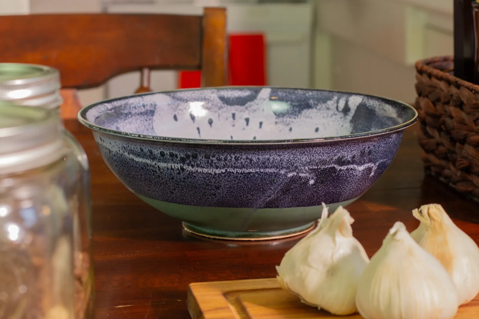 The empty bowl beside two heads of garlic on a cutting board.