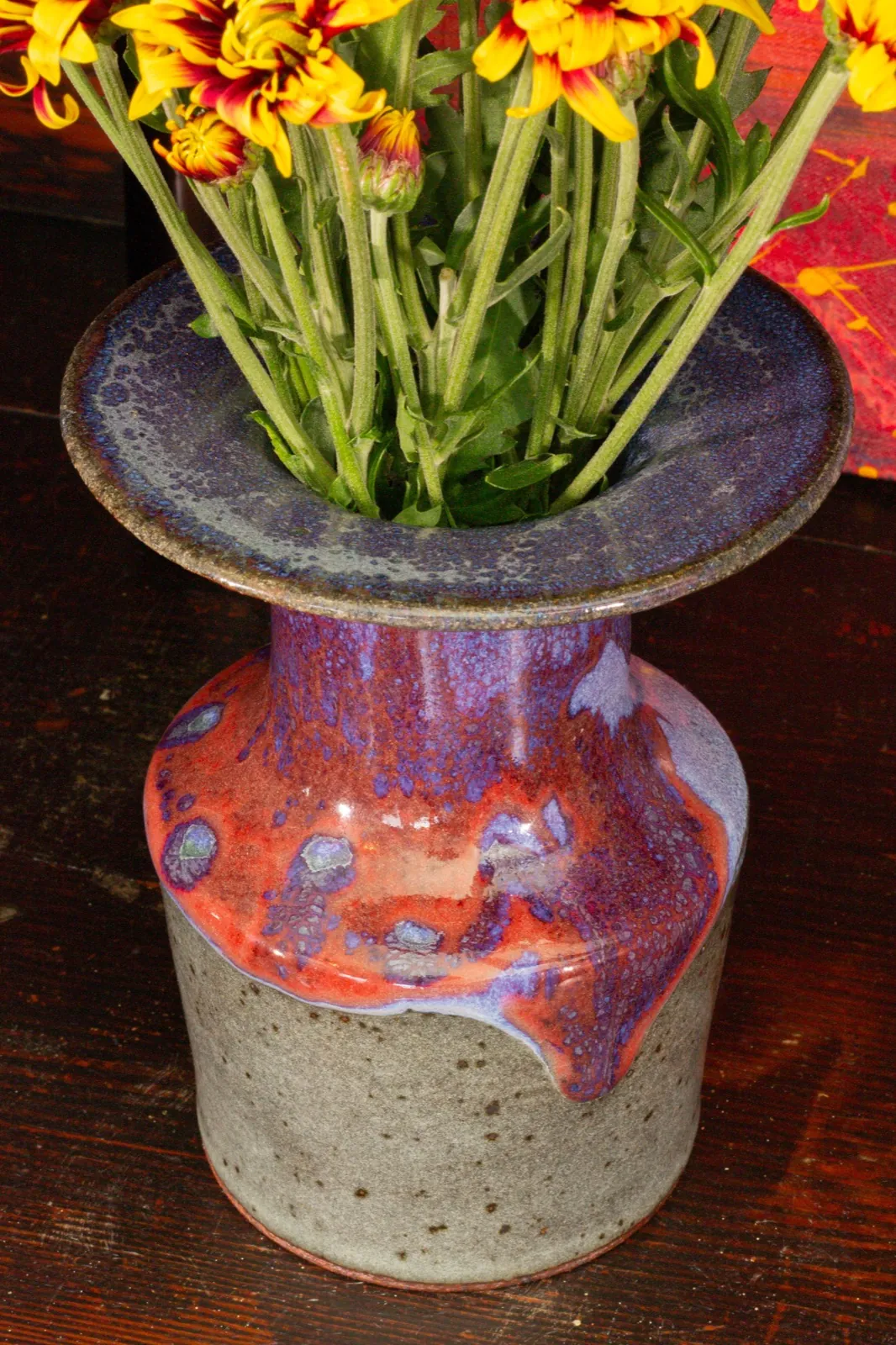 Three-quarter view of the bottle, showing how the red glaze pools and drips over the shoulder.