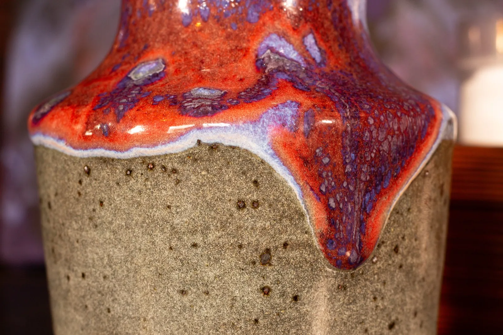 Macro detail of the copper red glaze breaking into purple over a speckled grey clay body.